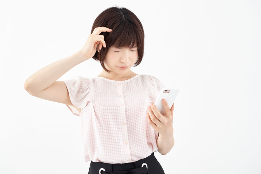 女性がスマートフォンでホームページを見ているが、スマートフォンに対応していないためストレスを感じている